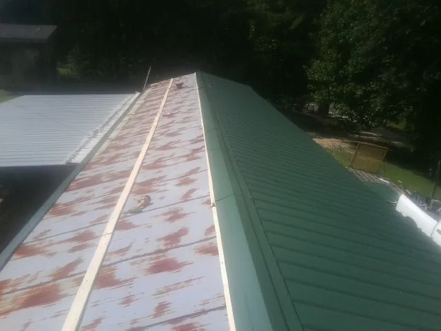 Old rusted panels beside newly installed green metal roofing — Wind Damage Roof Repair by Roofing Brothers in Pottersdale