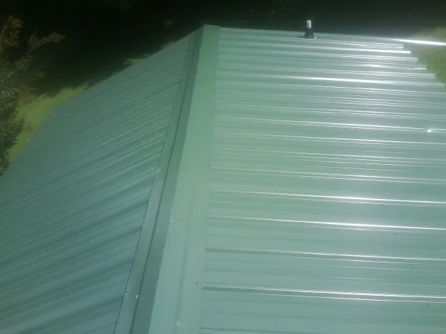 New green metal panels meeting at the ridge of a roof — Flat Roof Repair work by our crew in Pottersdale