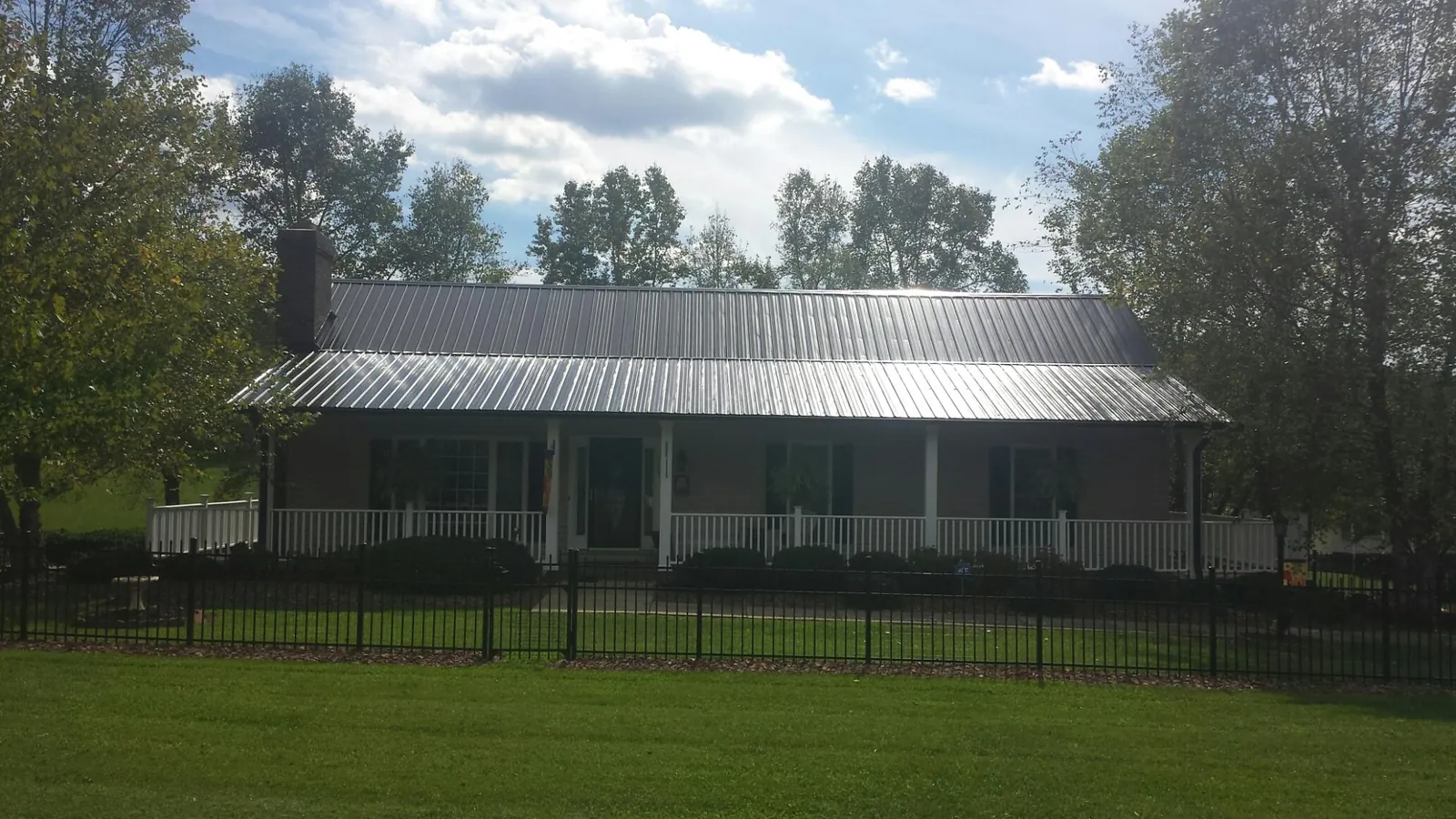Gray metal roof on a brick ranch with a full width front porch — Gutter Guard Installation work by our crew in Pottersdale
