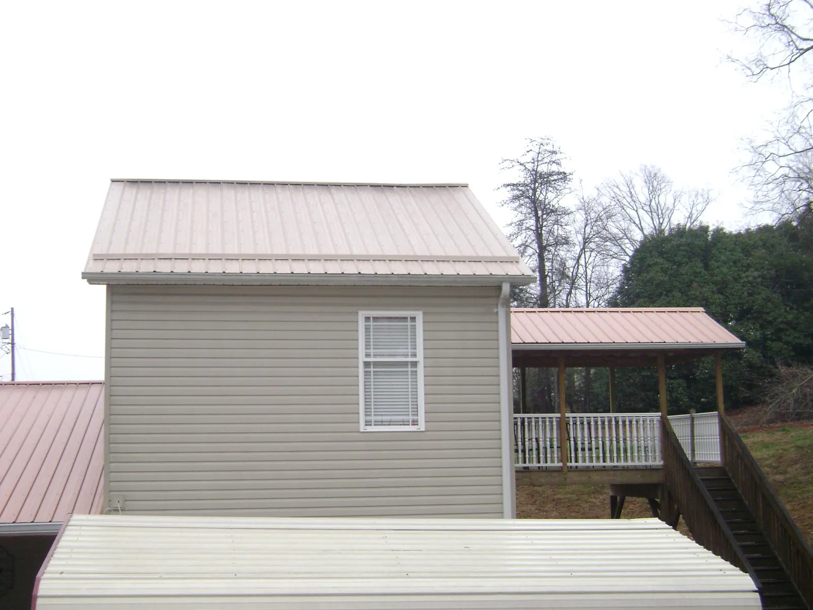 Tan metal roofs on a two story addition and attached porch, from a Roof Replacement job in Pottersdale