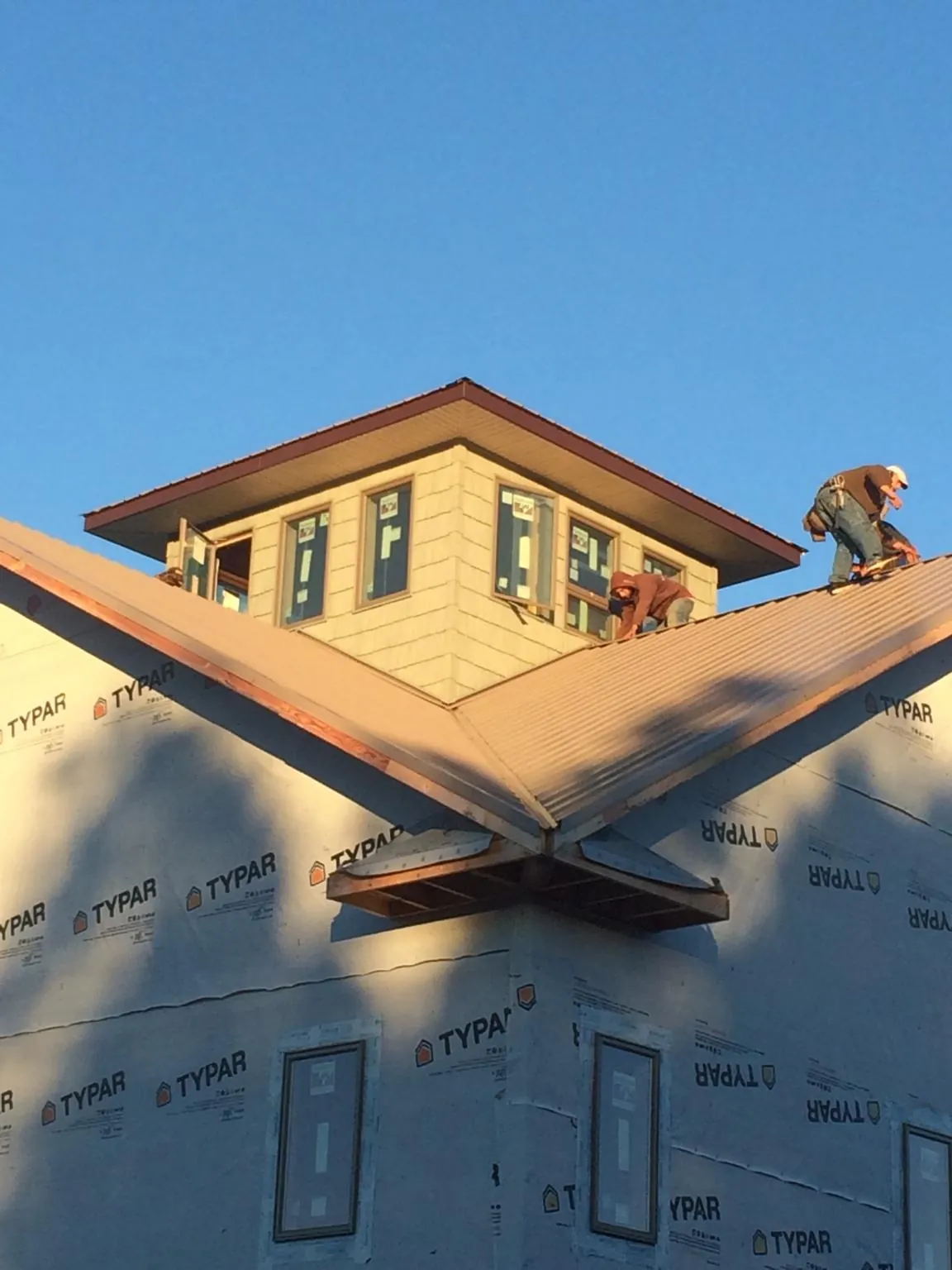Roofers working around a rooftop cupola on a new metal roof at sunset — Roof Waterproofing in Pottersdale by Roofing Brothers